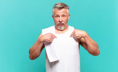 Son sınıf sporcusu mutlu, şaşkın ve gururlu hissediyor. Heyecanlı ve şaşkın bir bakışla kendini işaret ediyor.