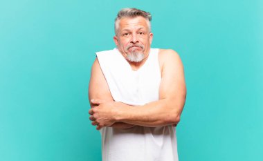 Kıdemli atlet omuz silkiyor, kafası karışık ve emin değil, kolları bağlı ve şaşkın görünüyor.