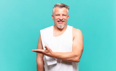 Son sınıf sporcusu neşeli bir şekilde gülümsüyor, mutlu hissediyor ve fotokopi alanında avuç içiyle bir konsept gösteriyor.