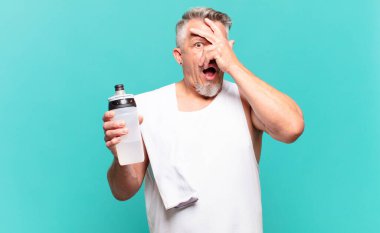 Son sınıf sporcusu şok olmuş, korkmuş ya da korkmuş görünüyor. Yüzü elle kaplanmış ve parmaklarının arasından gizlice bakıyor.