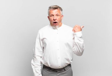 Kıdemli işadamı inançsızlıktan şaşkın şaşkın bakıyor, yan taraftaki objeyi işaret ediyor ve diyor ki: