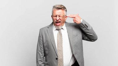 Kıdemli işadamı mutsuz ve stresli görünüyor, intihar jesti elle silah işareti yapıyor, kafasını işaret ediyor.