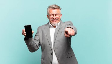 Üst düzey işadamı kameraya tatmin olmuş, kendinden emin, dostane bir gülümsemeyle bakıyor ve seni seçiyor.