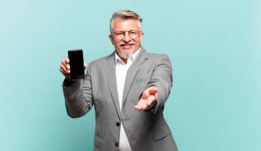 kıdemli işadamı mutlu bir şekilde gülümsüyor, güveni tam, olumlu bakışlı, bir nesne ya da konsept sunuyor ve gösteriyor.