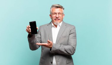 Kıdemli iş adamı mutlu bir şekilde gülümser, mutlu hisseder ve fotokopi alanında avucunun içinde bir konsept gösterir.