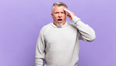 old senior man looking happy, astonished and surprised, smiling and realizing amazing and incredible good news