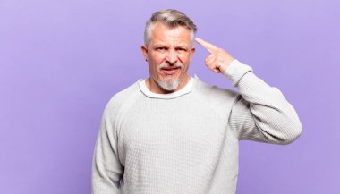 old senior man feeling confused and puzzled, showing you are insane, crazy or out of your mind