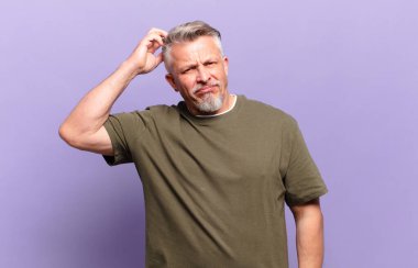 old senior man feeling puzzled and confused, scratching head and looking to the side