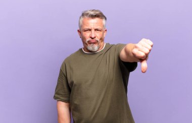 old senior man feeling cross, angry, annoyed, disappointed or displeased, showing thumbs down with a serious look