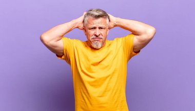 old senior man feeling stressed, worried, anxious or scared, with hands on head, panicking at mistake