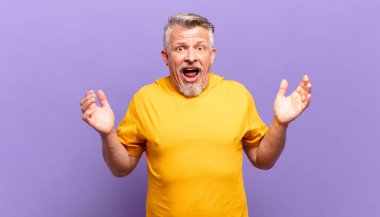 old senior man feeling happy, excited, surprised or shocked, smiling and astonished at something unbelievable