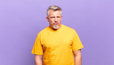old senior man feeling sad, upset or angry and looking to the side with a negative attitude, frowning in disagreement