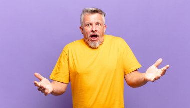 old senior man feeling extremely shocked and surprised, anxious and panicking, with a stressed and horrified look