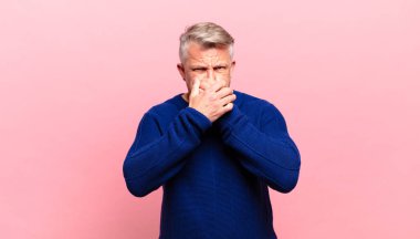 old senior man covering mouth with hands with a shocked, surprised expression, keeping a secret or saying oops