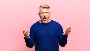old senior man feeling extremely shocked and surprised, anxious and panicking, with a stressed and horrified look