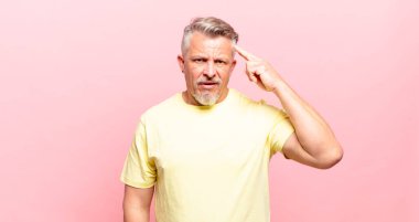 old senior man feeling confused and puzzled, showing you are insane, crazy or out of your mind