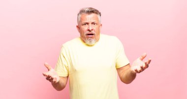 old senior man feeling extremely shocked and surprised, anxious and panicking, with a stressed and horrified look