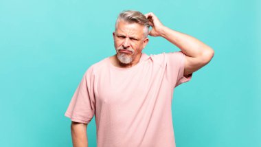 old senior man feeling puzzled and confused, scratching head and looking to the side