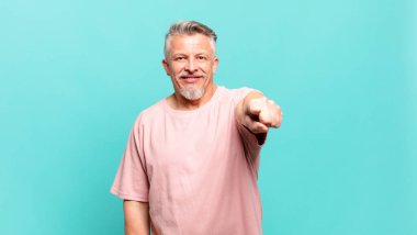 old senior man pointing at camera with a satisfied, confident, friendly smile, choosing you