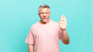 old senior man looking serious, stern, displeased and angry showing open palm making stop gesture