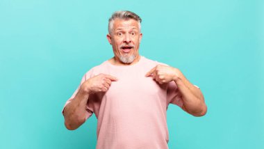 old senior man feeling happy, surprised and proud, pointing to self with an excited, amazed look