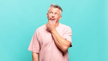 old senior man thinking, feeling doubtful and confused, with different options, wondering which decision to make