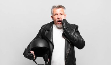 Son sınıf motosiklet sürücüsü şok olmuş ve korkmuş hissediyor, ağzı açık ve elleri yanaklarında.