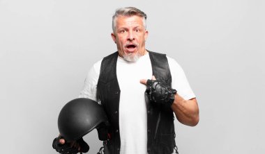 Son sınıf motosiklet sürücüsü şok olmuş ve ağzı açık bir şekilde kendini işaret ederek şaşırmış görünüyor.