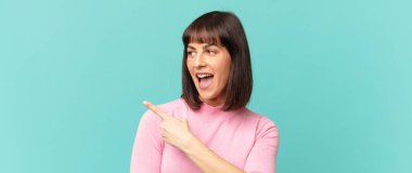 Güzel bir kadın heyecanlı ve şaşırmış görünüyor. Yana ve yukarı doğru uzayı gösteriyor.