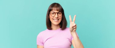 Güzel bir kadın gülümsüyor ve arkadaş canlısı görünüyor. İki ya da iki numarayı gösteriyor. Elleri önde, geri sayıyor.