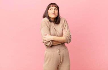 Güzel bir kadın omuz silkiyor, şaşkın ve kararsız hissediyor, kolları bağlı ve şaşkın bir şekilde şüpheye düşüyor.