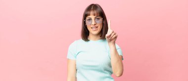 Güzel bir kadın gururla gülümsüyor ve gururla bir numaralı pozunu veriyor, kendini lider gibi hissediyor.