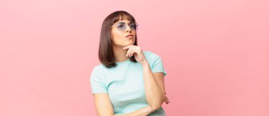 Güzel bir kadın düşünüyor, kuşkulu ve şaşkın hissediyor, farklı seçeneklerle, hangi kararı vereceğini merak ediyor.