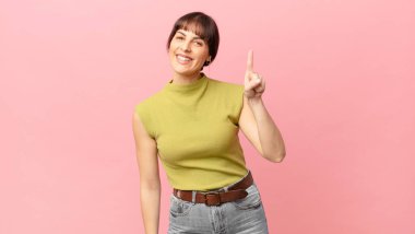 Güzel bir kadın gülümsüyor ve arkadaş canlısı görünüyor. Bir numarayı gösteriyor ya da ilk eli önde, geri sayıyor.