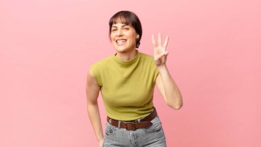 Güzel bir kadın gülümsüyor ve arkadaş canlısı görünüyor. Üç ya da üç numarayı gösteriyor. Elleri önde, geri sayıyor.