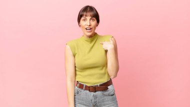 Şok olmuş ve ağzı açık, kendini işaret eden güzel bir kadın.