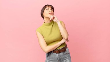 Güzel bir kadın düşünüyor, kuşkulu ve şaşkın hissediyor, farklı seçeneklerle, hangi kararı vereceğini merak ediyor.