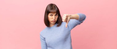 Güzel bir kadın sinirli, sinirli, sinirli, hayal kırıklığına uğramış ya da hoşnutsuz, ciddi bir bakışla başparmaklarını göstermiyor.