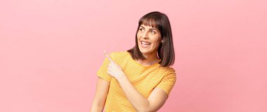 Güzel bir kadın heyecanlı ve şaşırmış görünüyor. Yana ve yukarı doğru uzayı gösteriyor.