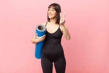 athlete woman smiling and looking happy, carefree and positive, gesturing victory or peace with one hand