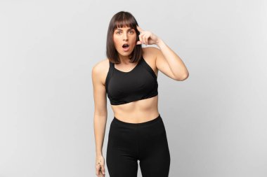 athlete woman looking surprised, open-mouthed, shocked, realizing a new thought, idea or concept