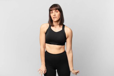 athlete woman looking puzzled and confused, biting lip with a nervous gesture, not knowing the answer to the problem