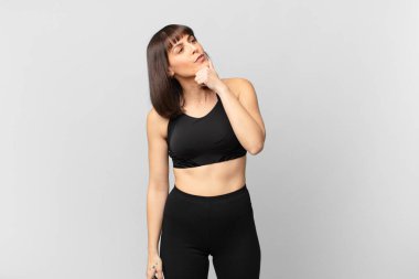 athlete woman thinking, feeling doubtful and confused, with different options, wondering which decision to make
