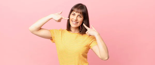 Hübsche Frau Lächelt Selbstbewusst Und Zeigt Auf Ihr Eigenes Breites — Stockfoto