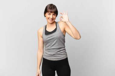 athlete woman feeling happy, relaxed and satisfied, showing approval with okay gesture, smiling