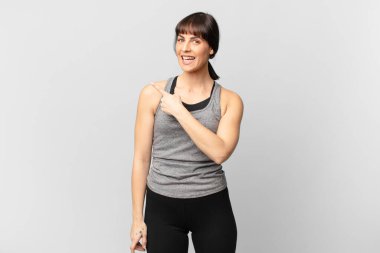 athlete woman looking excited and surprised pointing to the side and upwards to copy space