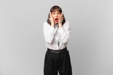 Tele pazarlamacı kadın şok olmuş ve korkmuş hissediyor, ağzı açık ve elleri yanaklarında korkmuş görünüyor.