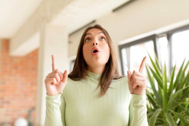 Güzel bir kadın şaşkınlık ve şaşkınlık dolu bir bakışla yukarıyı işaret ederek huşu içinde ve ağzı açık hisseder.