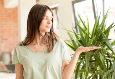 Güzel bir kadın kendini mutlu hisseder ve gelişigüzel gülümser. Elinde tuttuğu bir nesneye ya da konsepte bakar.