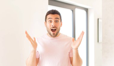 Yakışıklı adam mutlu, heyecanlı, şaşırmış ya da şaşırmış, gülümseyen ve hayrete düşmüş.